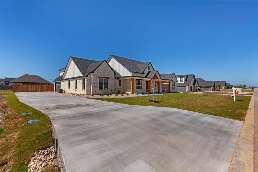 Modern farmhouse style home with stone siding, covered porch, a residential view, driveway, and board and batten siding Modern farmhouse style home with stone siding, covered porch, a residential view, driveway, and board and batten siding