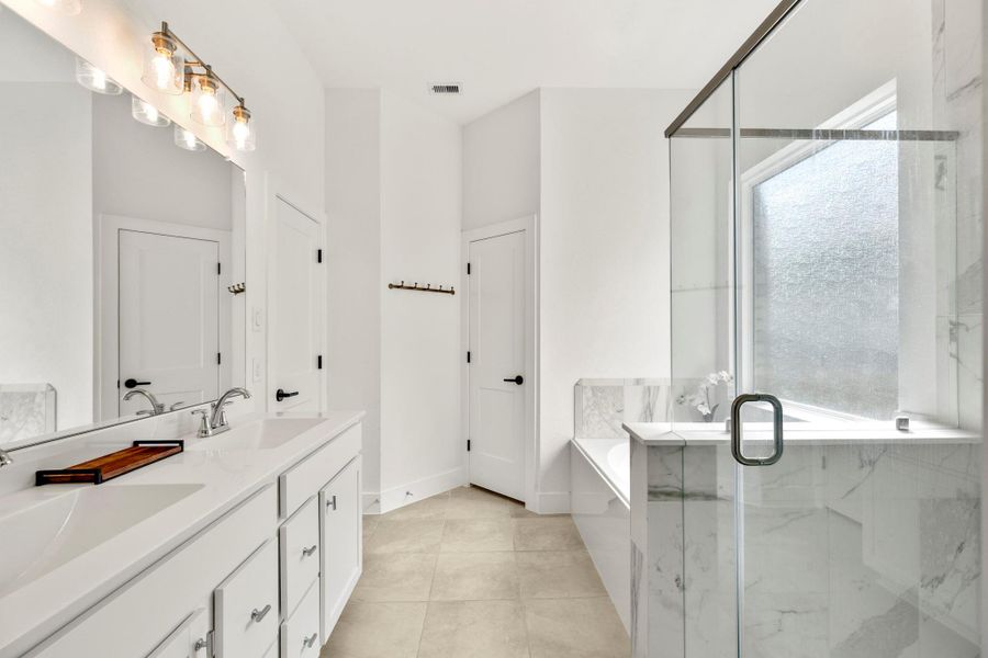 This primary bathroom features a modern design with a double vanity, sleek countertops, and stylish light fixtures. It includes a spacious glass-enclosed shower, a separate bathtub. This primary bathroom features a modern design with a double vanity, sleek countertops, and stylish light fixtures. It includes a spacious glass-enclosed shower, a separate bathtub.