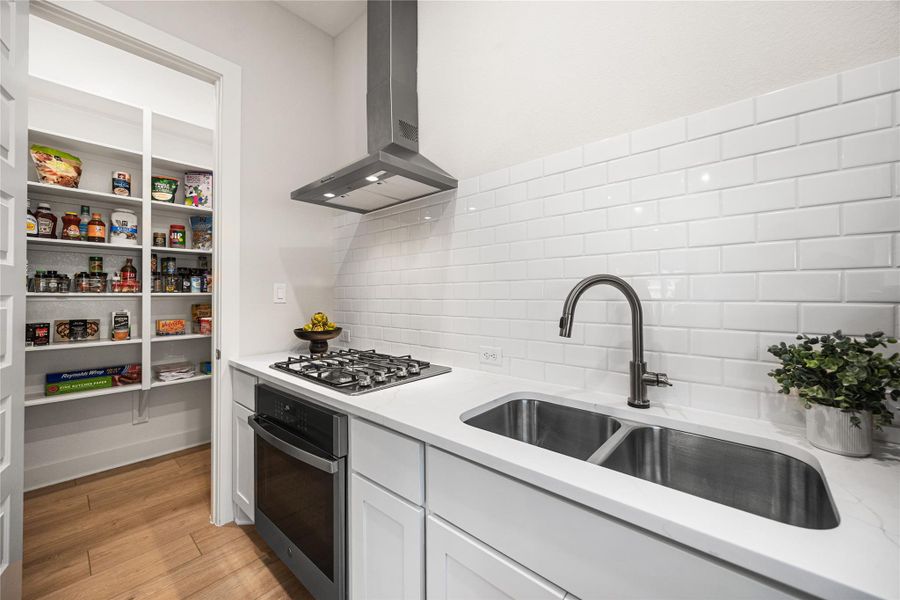 The fully equipped prep kitchen features its own stove, oven, and sink, providing the perfect space for meal prep while keeping the main kitchen clean and ready for entertaining.