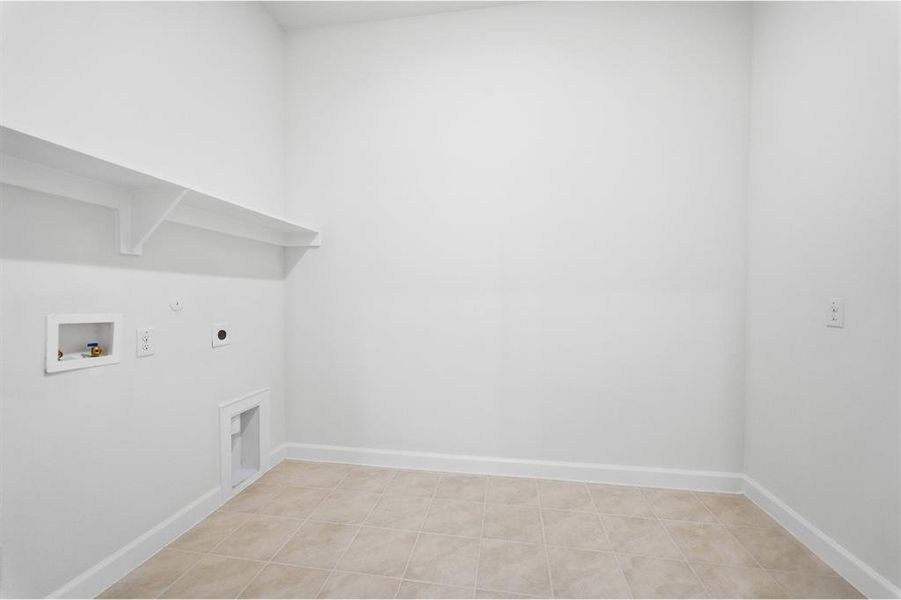 Utility room with neutral tile flooring and white baseboards