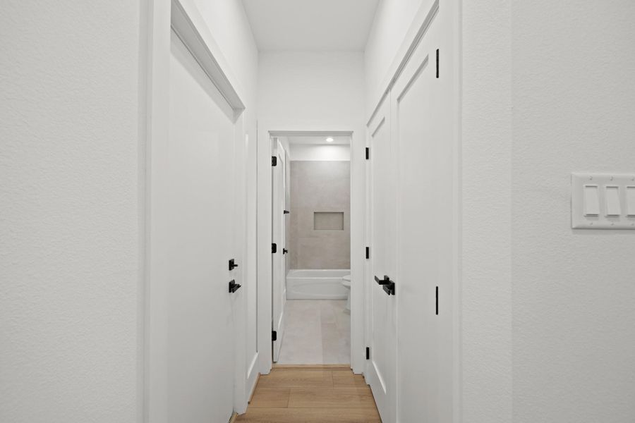 This is the hallway that leads to the bathroom, featuring a convenient storage closet on the right and direct access to the private backyard on the left. This is the hallway that leads to the bathroom, featuring a convenient storage closet on the right and direct access to the private backyard on the left.