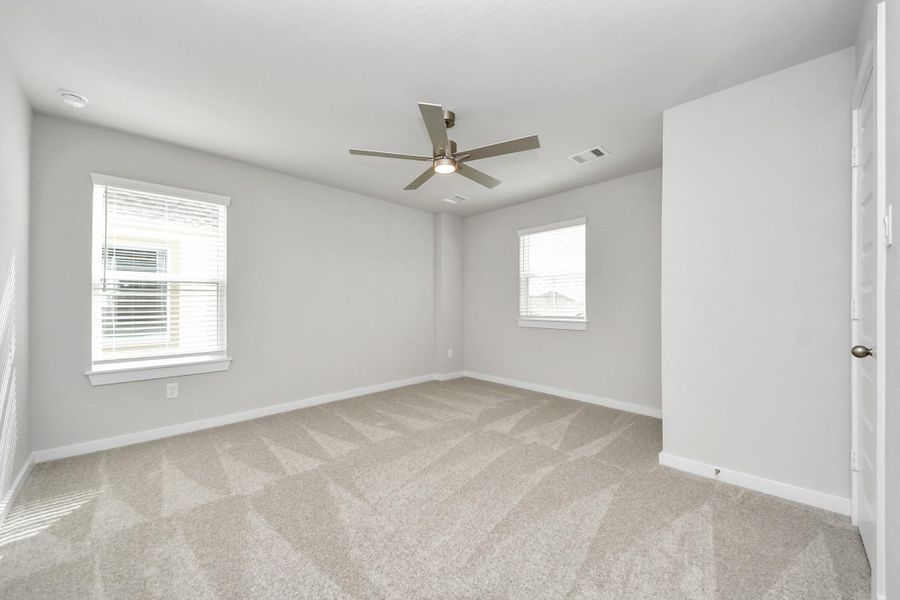 Secondary bedroom features plush carpeting, large windows that let in plenty of natural light, bright paint, and spacious closets.