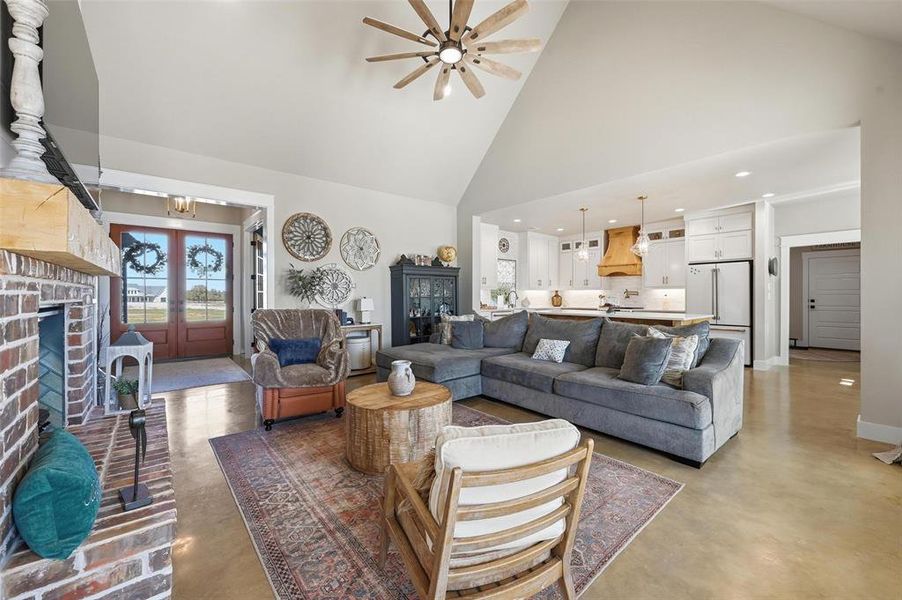 Living area featuring finished concrete floors, high vaulted ceiling, recessed lighting, a ceiling fan, and french doors Living area featuring finished concrete floors, high vaulted ceiling, recessed lighting, a ceiling fan, and french doors