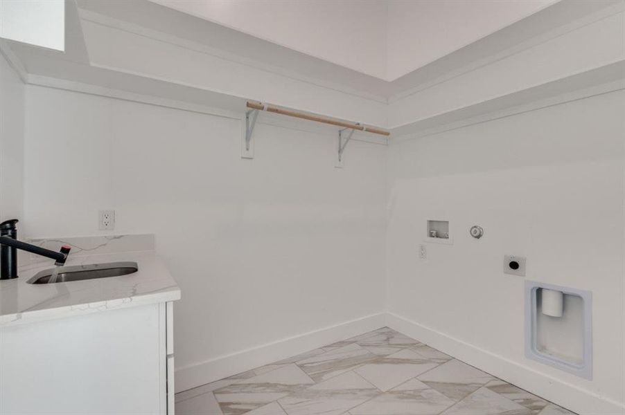 Laundry room with a sink featuring a temperature gauge on the faucet and a wall outlet for a TV—functional and convenient. Laundry room with a sink featuring a temperature gauge on the faucet and a wall outlet for a TV—functional and convenient.