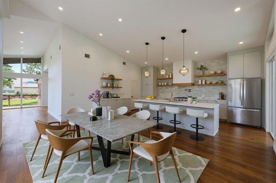 Dining space with dark wood-style floors, a high ceiling, and recessed lighting