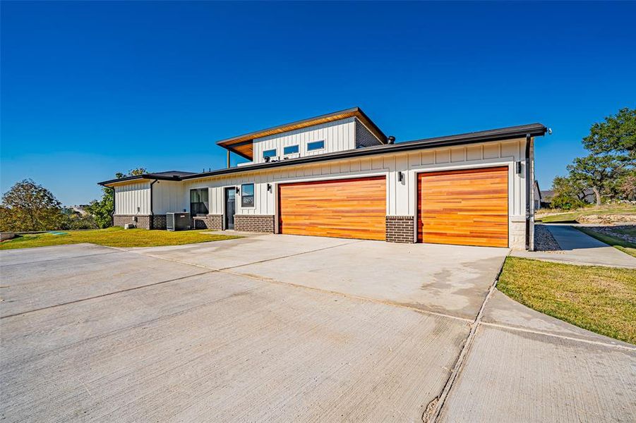 Contemporary home featuring board and batten siding, concrete driveway, a front yard, and a garage Contemporary home featuring board and batten siding, concrete driveway, a front yard, and a garage