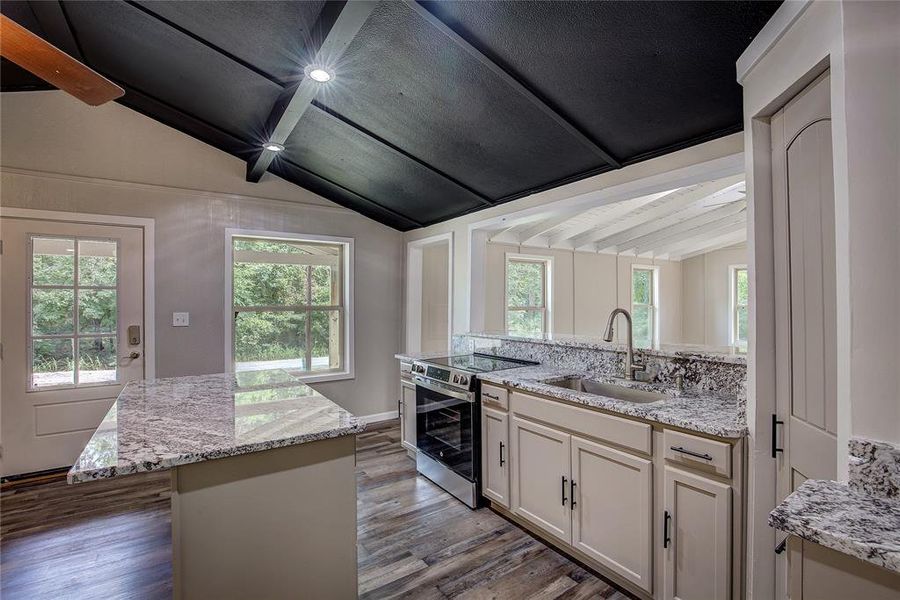 Kitchen featuring electric range, hardwood / wood-style flooring, vaulted ceiling with beams, and sink