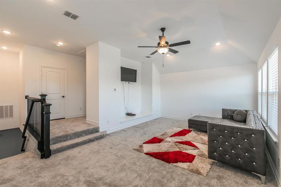 Living area with ceiling fan, carpet floors, and lofted ceiling