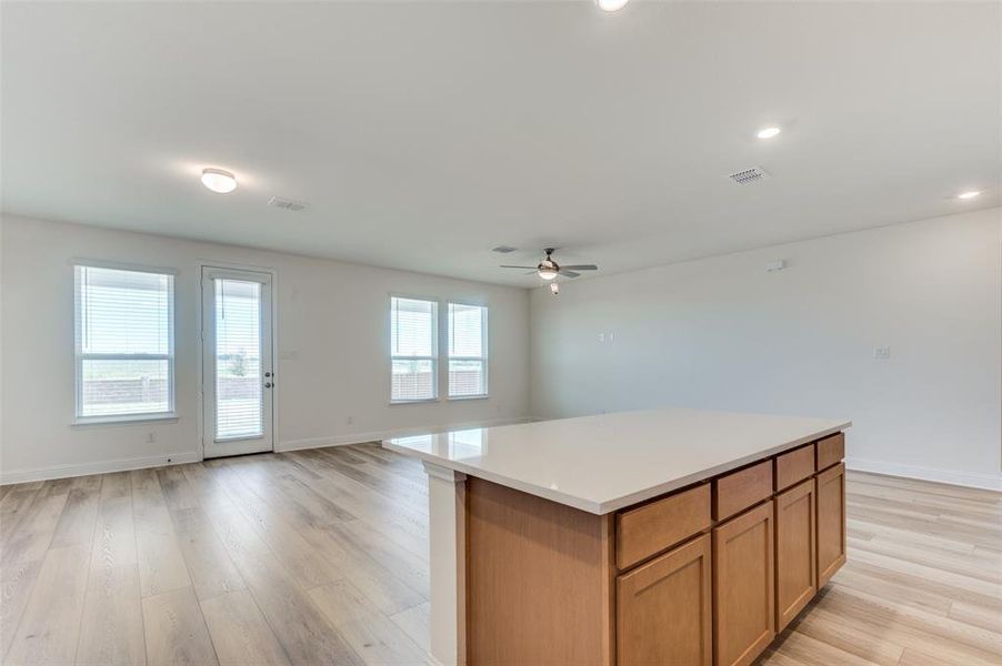Kitchen with light wood-style floors, ceiling fan, a kitchen island, light countertops, and recessed lighting