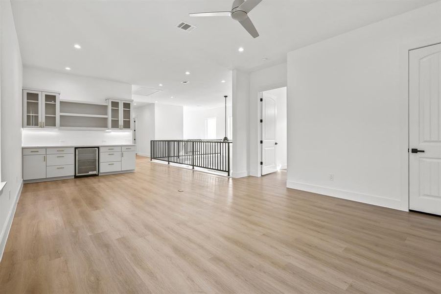 Unfurnished living room with ceiling fan, light hardwood / wood-style floors, and beverage cooler