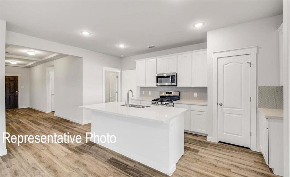 Kitchen featuring light hardwood / wood-style floors, white cabinetry, sink, and stainless steel appliances