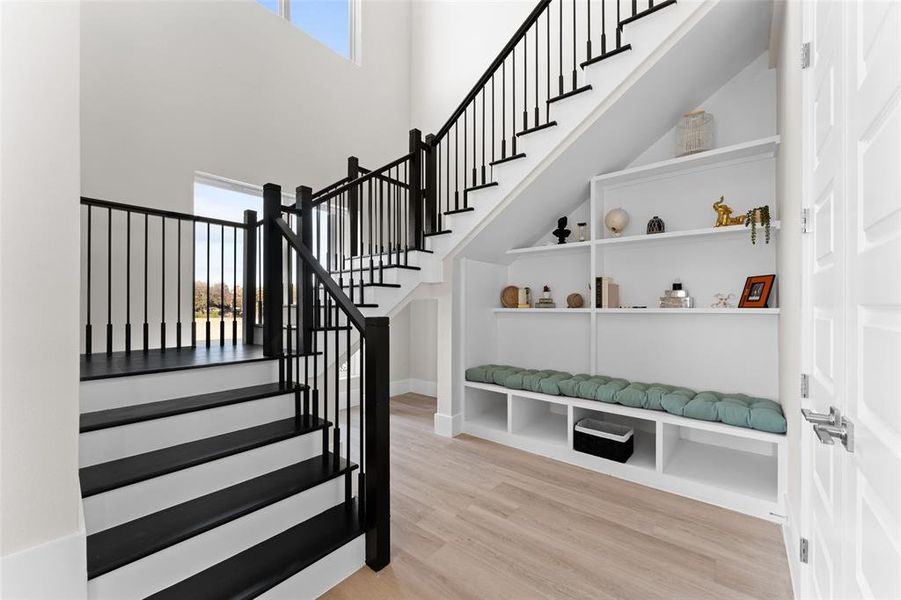 Stairs with plenty of natural light, wood finished floors, and a high ceiling Stairs with plenty of natural light, wood finished floors, and a high ceiling