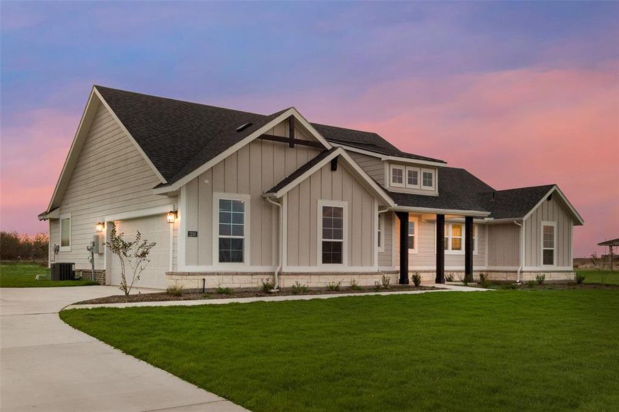 View of front of home featuring roof with shingles, a front yard, board and batten siding, and concrete driveway