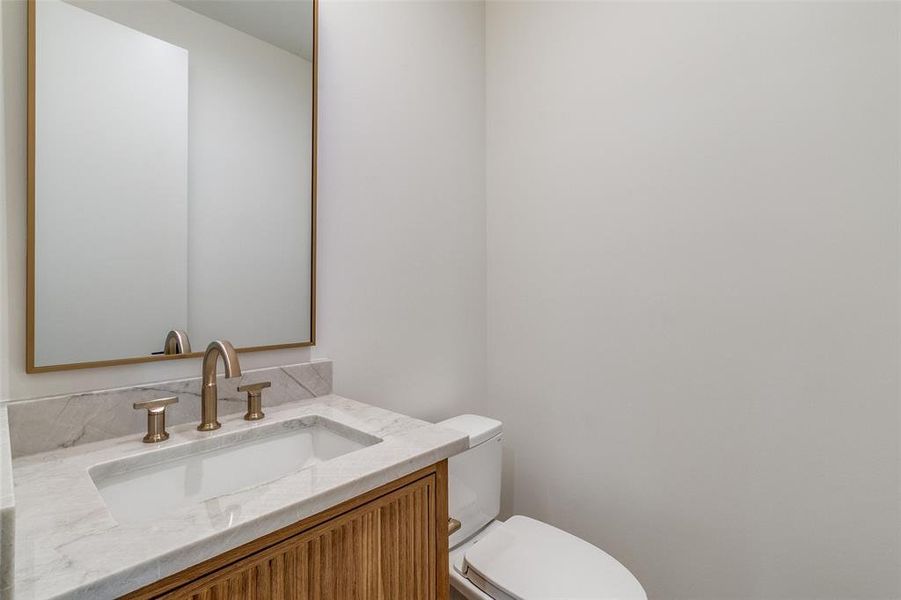 Half bath featuring vanity and toilet Half bath featuring vanity and toilet