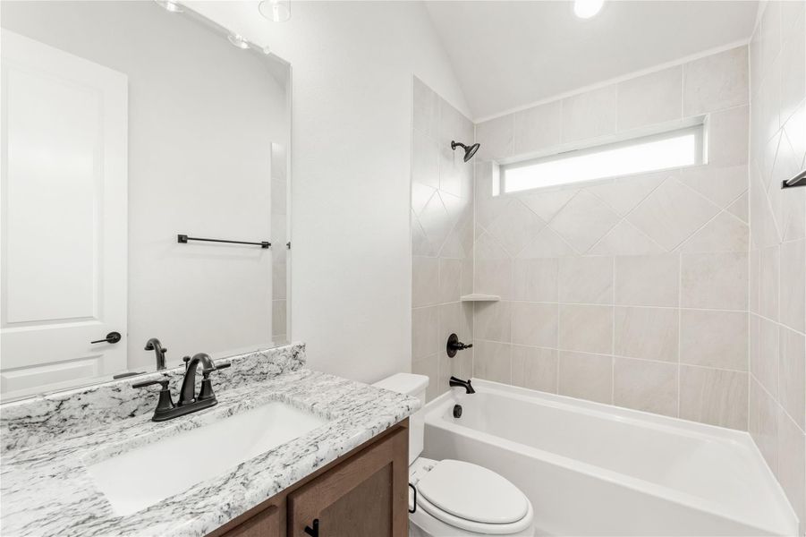 Bathroom with granite vanity, tub-shower combo with tile surround, and vaulted ceiling