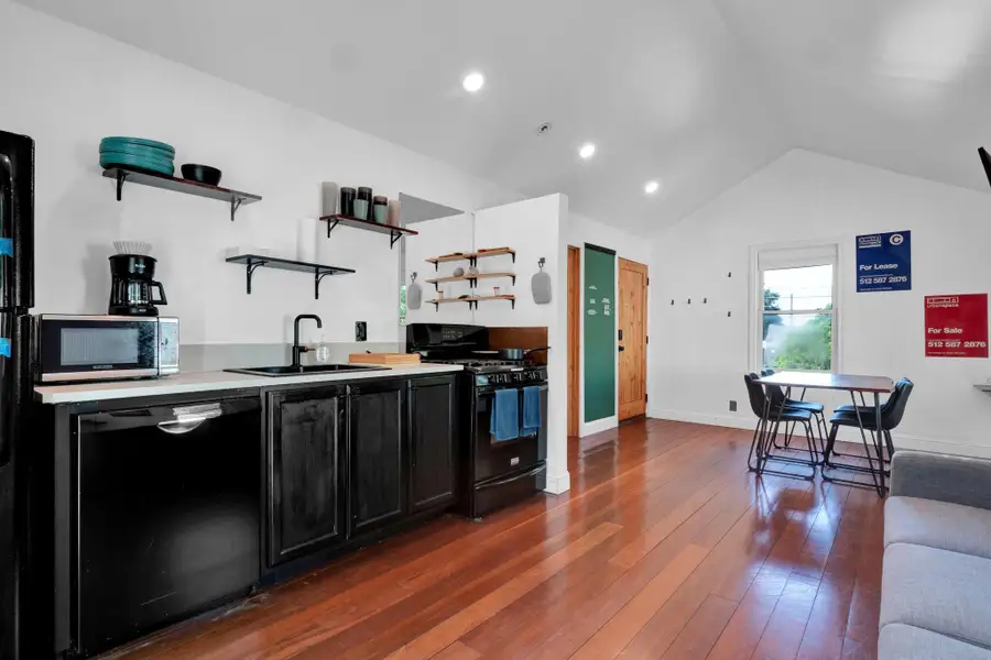 Kitchen with black appliances, open shelves, dark cabinetry, vaulted ceiling, and dark wood-type flooring