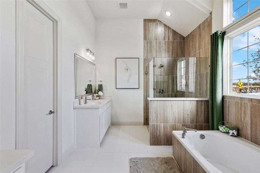 Bathroom featuring a dual vanity with undermount sinks, a walk-in shower with glass enclosure, a built-in soaking tub, wood-look tiled walls, and large windows