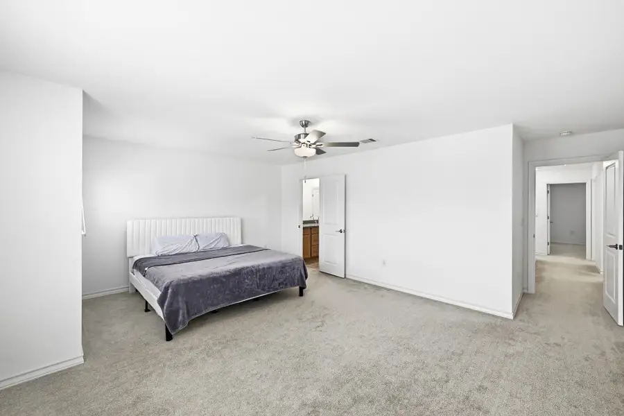 Bedroom with light carpet, ceiling fan, and ensuite bath