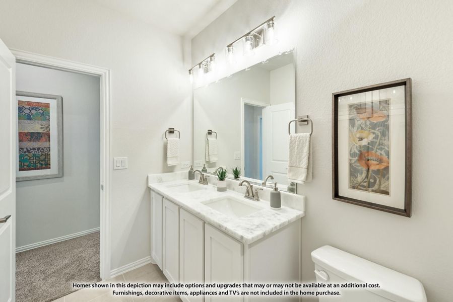 Bathroom with double sink vanity, white cabinets, marble countertop, and large mirror with overhead lighting