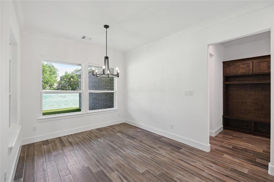 Unfurnished dining area with hardwood / wood-style flooring, ornamental molding, and an inviting chandelier