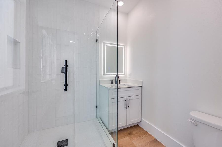 Full bathroom featuring a stall shower, vanity, and wood finished floors Full bathroom featuring a stall shower, vanity, and wood finished floors