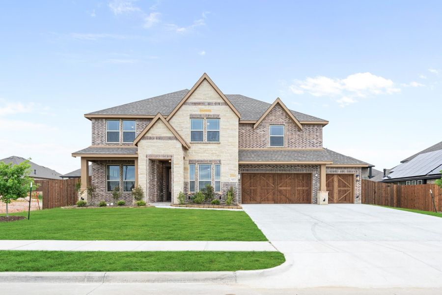 Two-story brick and stone home with three-car garage and manicured front lawn Two-story brick and stone home with three-car garage and manicured front lawn