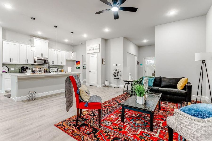 Living room with ceiling fan and light hardwood / wood-style floors