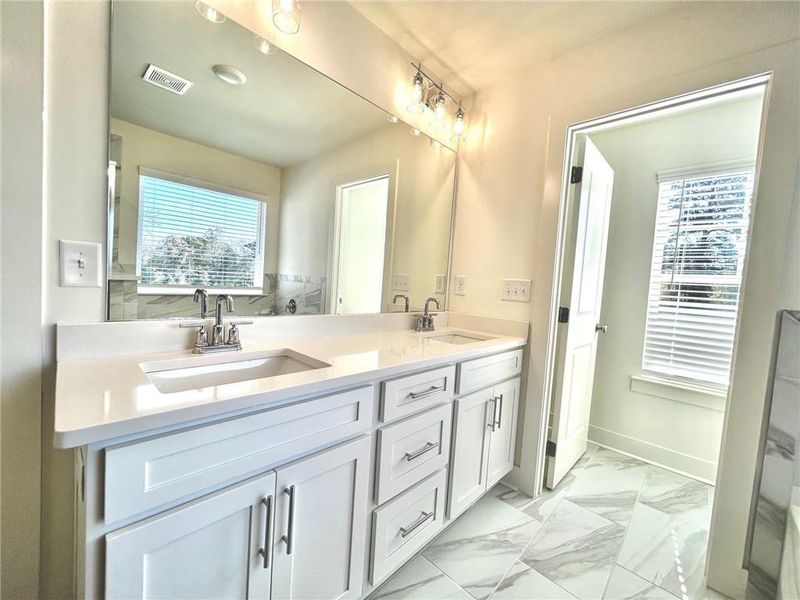 Bathroom featuring a healthy amount of sunlight, tile flooring, and dual bowl vanity