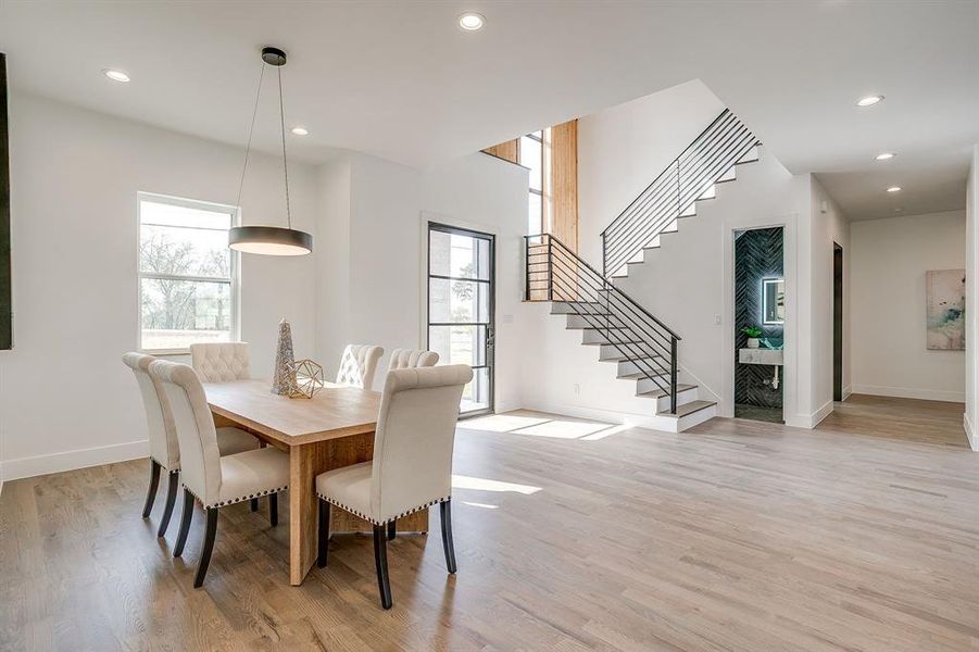 Dining area featuring recessed lighting, stairs, and light wood-style flooring Dining area featuring recessed lighting, stairs, and light wood-style flooring