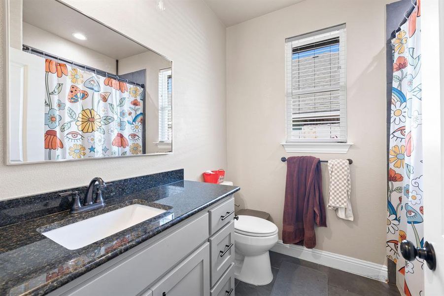 Bathroom with tile patterned floors, vanity, toilet, and a shower with curtain