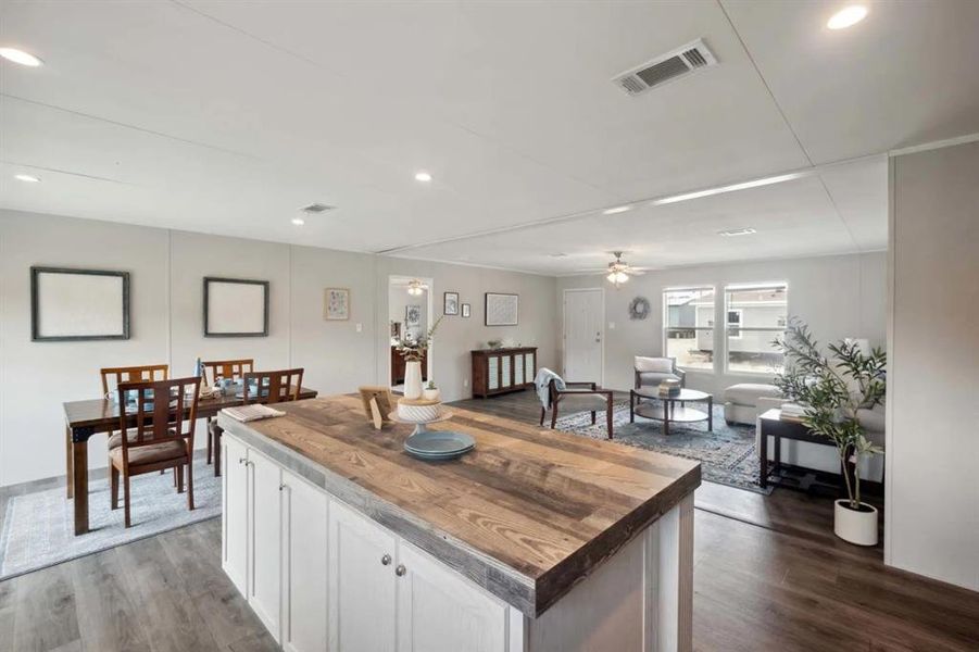 Kitchen featuring ceiling fan, a center island, dark hardwood / wood-style floors, butcher block countertops, and white cabinets