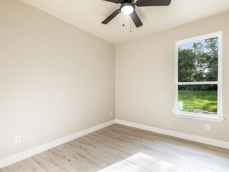 Empty room featuring healthy amount of natural light, wood finished floors, and ceiling fan Empty room featuring healthy amount of natural light, wood finished floors, and ceiling fan