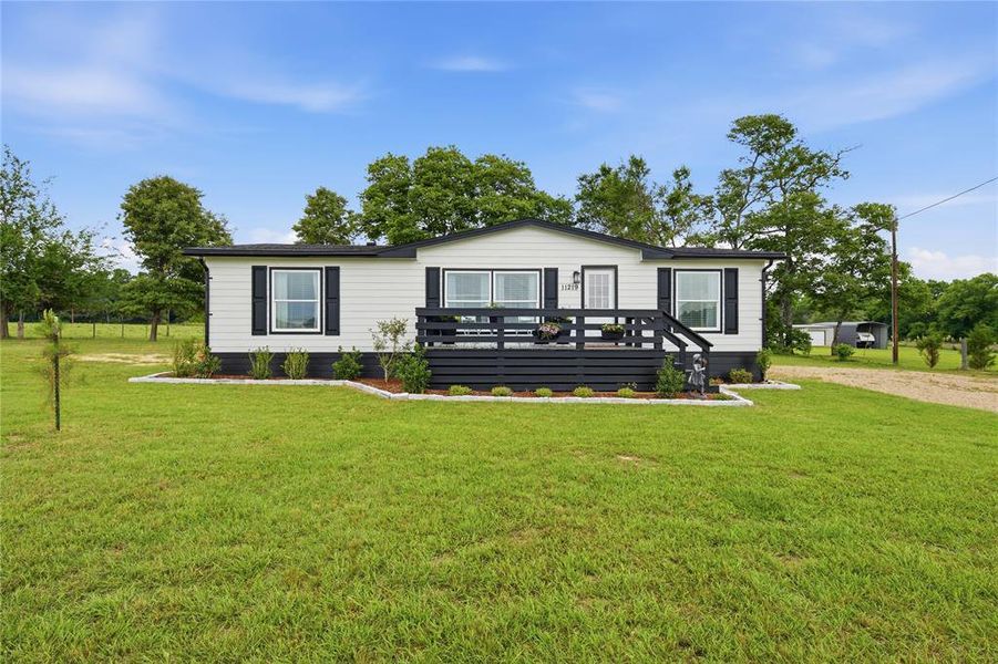 White exterior with black trim and shutters, featuring a prominent front deck with dark railings