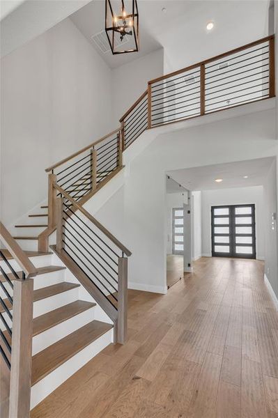 Staircase featuring hardwood / wood-style flooring, a chandelier, and a high ceiling