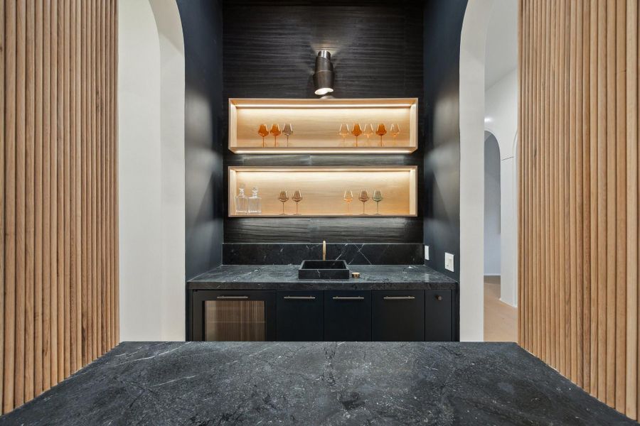 Incredible Wet-Bar with Arched openings, Leather finished Marble Counter with an intergrated sink. There is wall paper on the back wall, White Oak Box Shelving with LED Lighting, Single Modern Pendant Light, Panel Ready Under-Counter Refrigerator and a Panel Ready Ice Maker. The front of the Bar features a Waterfall Marble Counter and an Arched opening with White Oak Reeded Paneling. Incredible Wet-Bar with Arched openings, Leather finished Marble Counter with an intergrated sink. There is wall paper on the back wall, White Oak Box Shelving with LED Lighting, Single Modern Pendant Light, Panel Ready Under-Counter Refrigerator and a Panel Ready Ice Maker. The front of the Bar features a Waterfall Marble Counter and an Arched opening with White Oak Reeded Paneling.