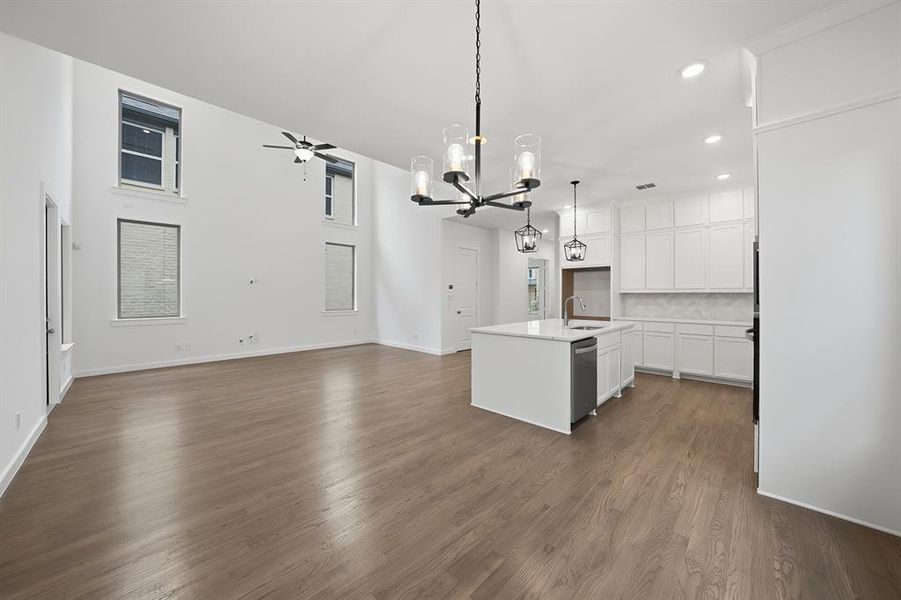 Kitchen featuring white cabinetry, an island with sink, decorative light fixtures, open floor plan, and a chandelier