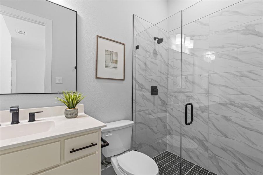 Full bathroom featuring vanity, a stall shower, and a textured wall