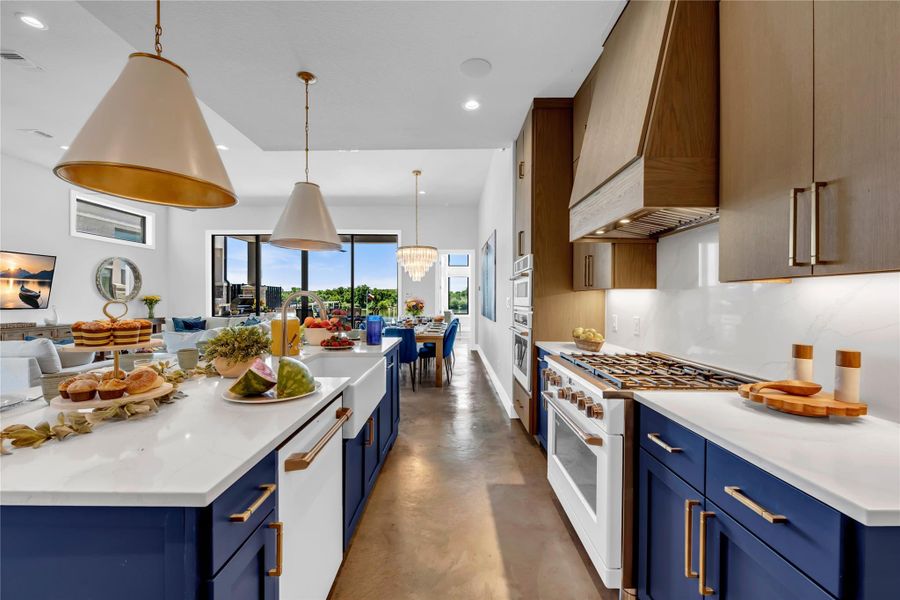 Gourmet kitchen featuring a large central island with a farmhouse sink, quartz countertops, and custom blue cabinetry