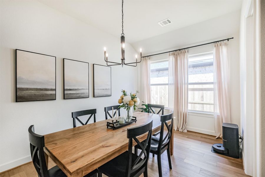 Formal dining room with modern chandelier and hardwood floors.