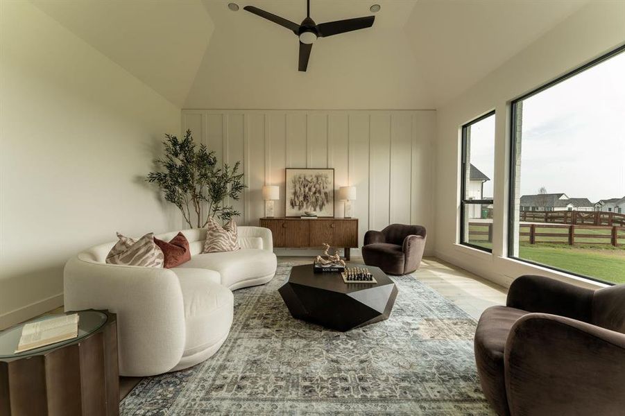 Living area featuring ceiling fan, wood finished floors, lofted ceiling, and a decorative wall Living area featuring ceiling fan, wood finished floors, lofted ceiling, and a decorative wall