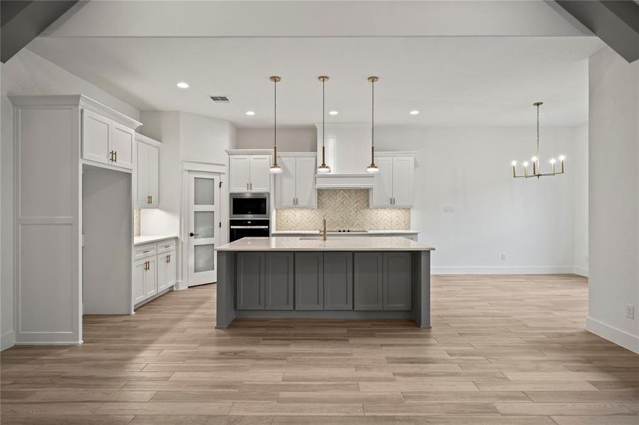 Kitchen featuring white cabinetry, hanging light fixtures, backsplash, light wood-style floors, and recessed lighting