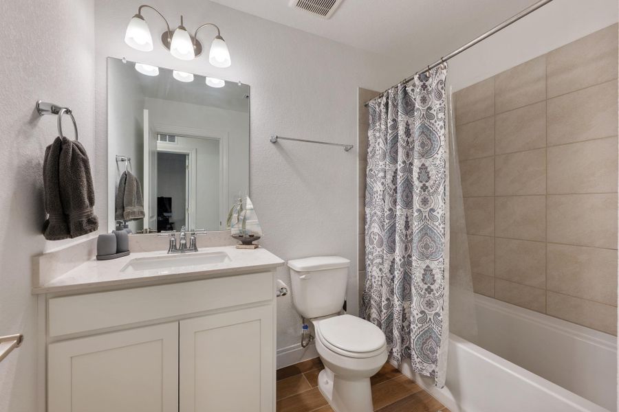A well-appointed bathroom features a single vanity, a standard toilet, and a tiled shower with a white tub. A well-appointed bathroom features a single vanity, a standard toilet, and a tiled shower with a white tub.