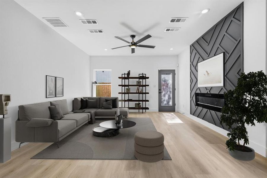 Living area with light wood-type flooring, an accent wall, a ceiling fan, and recessed lighting