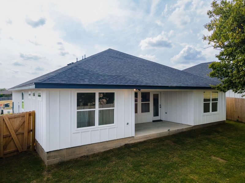 Rear view of house featuring a shingled roof, a patio area, and board and batten siding