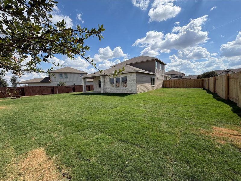 Back of property with a fenced backyard, stone siding, and a patio Back of property with a fenced backyard, stone siding, and a patio