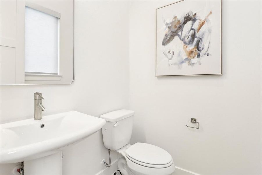 Half bathroom on second floor living featuring a sink, toilet, and baseboards