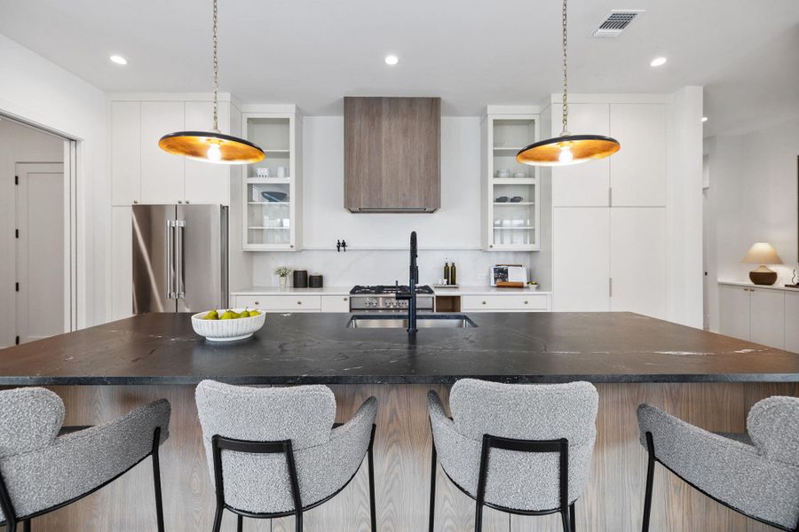 Kitchen featuring white cabinetry, a breakfast bar area, high quality fridge, recessed lighting, and a kitchen island with sink Kitchen featuring white cabinetry, a breakfast bar area, high quality fridge, recessed lighting, and a kitchen island with sink