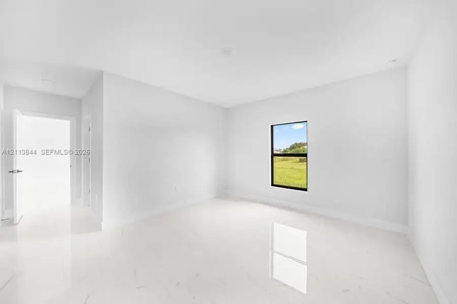 Interior space featuring large-format tile flooring, neutral wall paint, recessed lighting, and a single-pane window with black framing Interior space featuring large-format tile flooring, neutral wall paint, recessed lighting, and a single-pane window with black framing