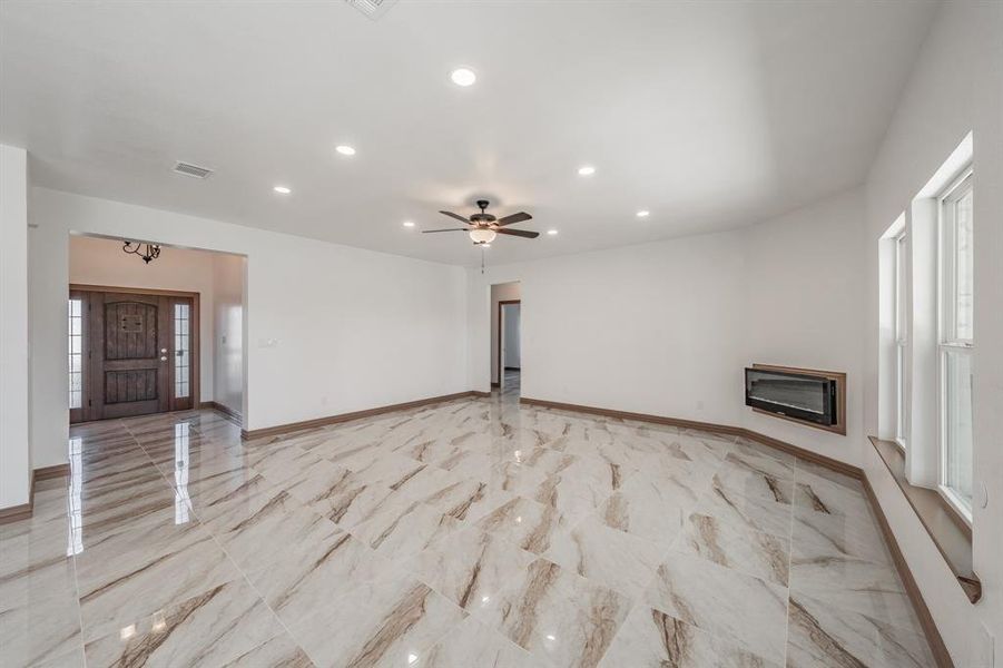 Unfurnished living room with marble finish floor, recessed lighting, visible vents, a glass covered fireplace, and baseboards