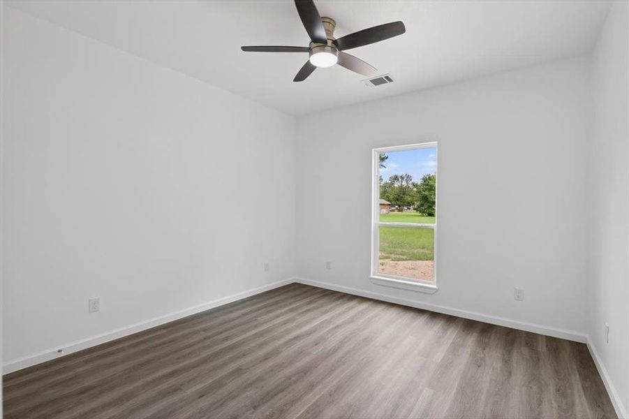 Bedroom 2 featuring a window with view to the backyard, LVP flooring, a ceiling fan with integrated lighting, and crisp white walls with white trim